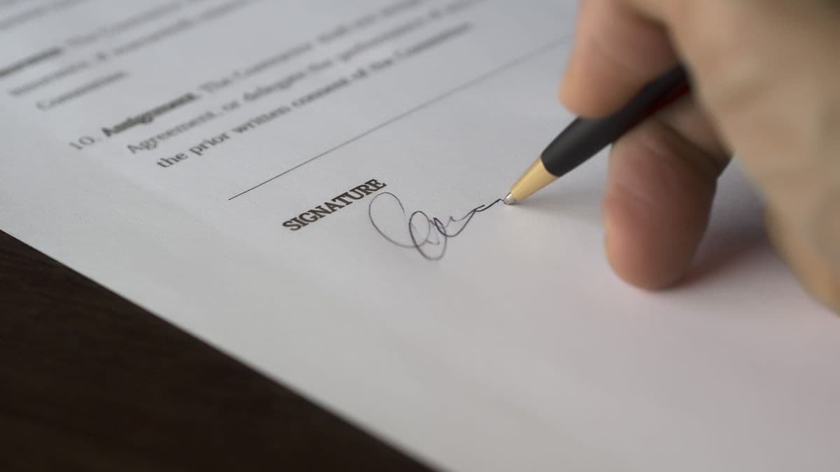 A person signing a formal contract with a pen