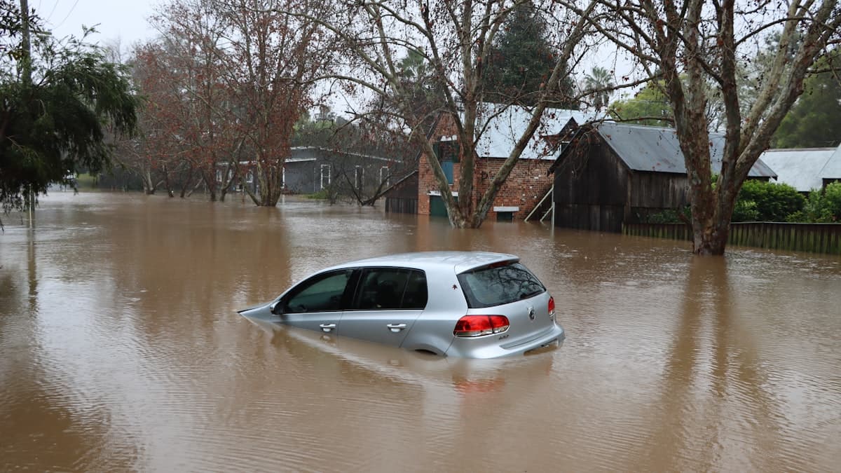 A car submerged to its windows on a flooded residential street