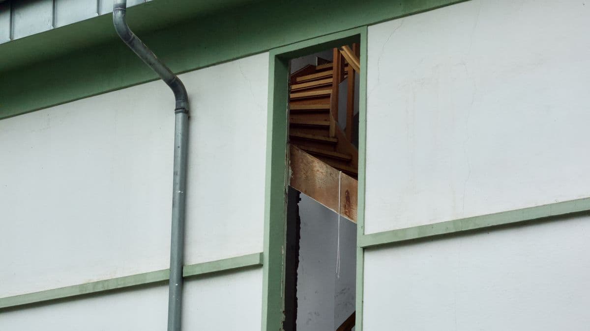 A house exterior with a damaged roof and exposed structure