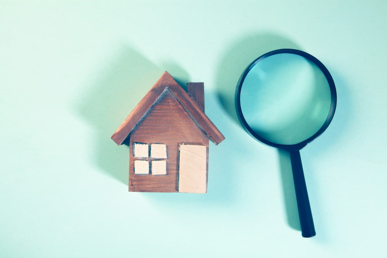 A magnifying glass over a wooden house model