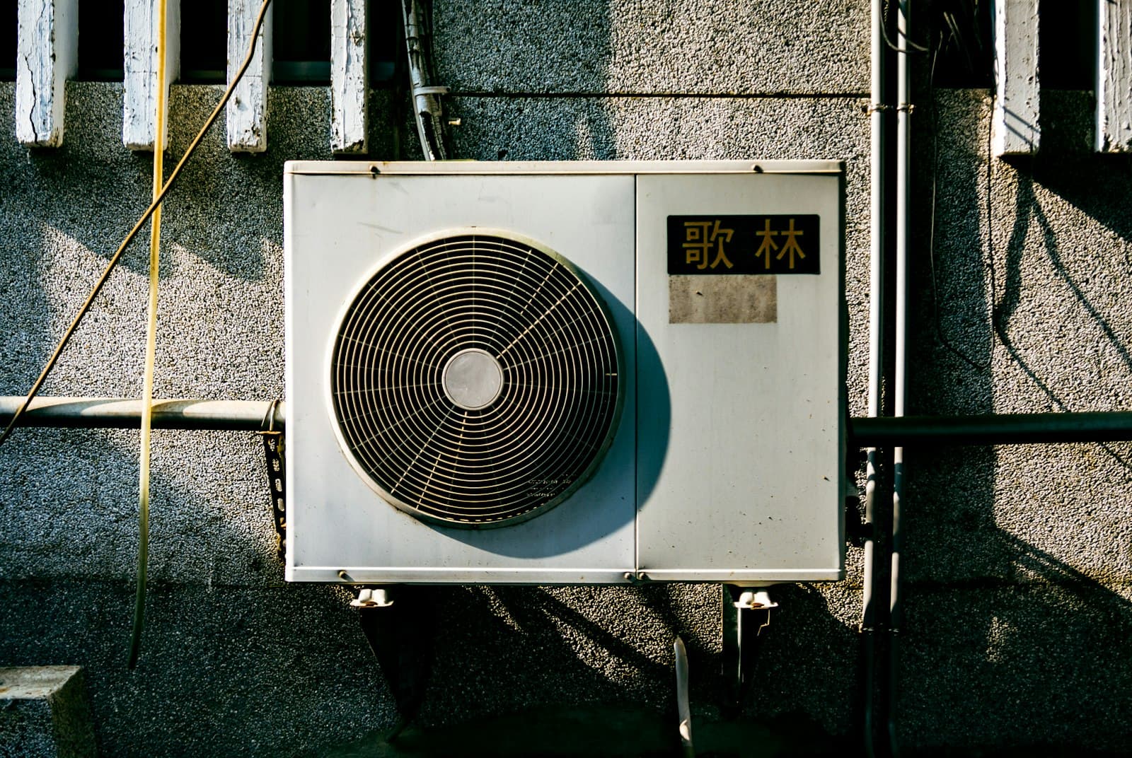 A heat-pump condenser mounted on an exterior wall